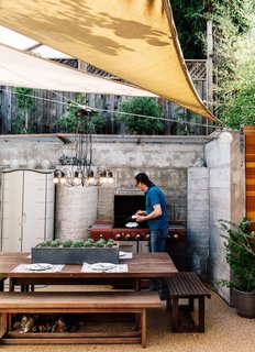 The new retaining wall at the rear of Todd and Carmen Cherniawsky’s 550-square-foot yard protects against damage caused by water and seismic activity. A Radial chandelier from CB2 hangs from nylon cords above a Jensen Jarrah dining set from Universal Patio Furniture. 