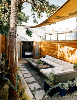 A wicker sectional from Target and a custom fire table that Todd designed sit under Sunbrella shade sails. 