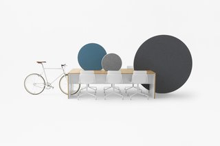 The slots made in the table accommodate a bicycle for commuters and various whiteboards to divide up space in the office. 