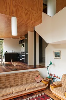 The mezzanine daybed is set in a windowed nook within shelves recycled from a Lundia system. Peta Tearle designed the color scheme and chose the black Melteca kitchen cupboards, which echo the exterior.