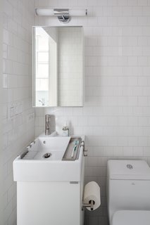 In the bathroom, a compact Lillången sink from IKEA offers a narrow profile for the tight space, yet is deep enough to accommodate hanging storage trays for toiletrie. The toilet is by Fresca and the subway tile is from Mosa. 