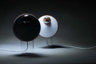 BeoLab S, designed by Tuomas Hämäläinen, aimed to combine the simplicity of one-point music systems with the wide sound stage of traditional stereo speaker systems. The warm, wooden loudspeakers perch atop translucent cylindrical stands. 