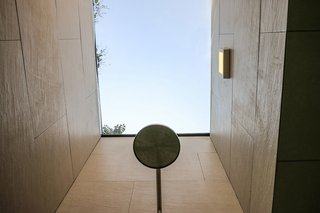 A custom aluminum-framed skylight with a 3M solar membrane floods the bathroom shower with light; the fixture is by Castel. 