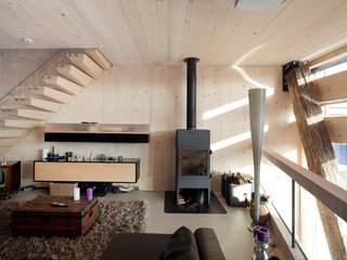 The pellet stove in the living room area serves multiple purposes including providing heat for the shower and the rooms on cold days.