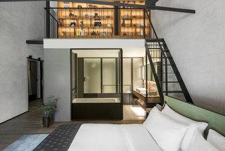 The hotel voluminous rooms with high ceilings, concrete walls, and exposed beams. Shown here is the River View Mezzanine that includes two levels, a library, and a view of the Singapore River.