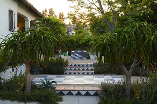 In this garden by Mark Tessier, tiled stairs with a modern pattern bring a geometric and playful touch to this traditional home.