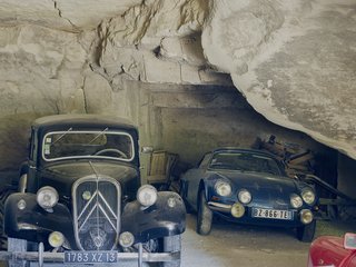 The fleet includes a ruby-red Renault Dauphine and a black Citroën Traction Avant.