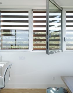 Cedar louvers veil hurricane windows by Solar Innovations.