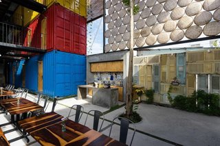 6 Well-Designed Hostels For the Minimalist Traveler - Photo 1 of 6 - Stacked shipping containers—painted red, blue, and yellow to distinguish the different room types—are arranged around a large socializing area for guests. 