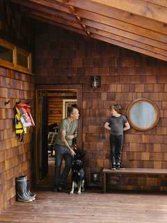 An Eclectic Pacific Northwest Cottage - Photo 1 of 13 - At the entrance, Bruce is joined by his son, Sozé, and dog, Izzy. The 1940s shingled cottage was renovated by architectural designer Randall Recinos, designer Brian Paquette, and contractor Dylan Conrad.