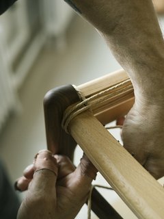 Warp Speed - Photo 5 of 12 - Benny carefully navigates the front corner of the CH23 dining chair, looping the cord to begin the weaving process. 