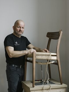 Warp Speed - Photo 2 of 12 - Master weaver Benny Hammer Larsen has worked for Danish furniture company Carl Hansen <br>& Søn for more than two decades. He travels the globe, demonstrating the meticulous techniques used to realize each piece. He stands next to the reintroduced CH23 dining chair, by Hans J. Wegner.