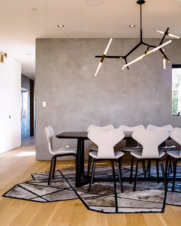 Fritz Hansen Grand Prix chairs, a Lindsey Adelman Agnes Chandelier, and a Kyle Bunting Runway rug furnish the dining room. 