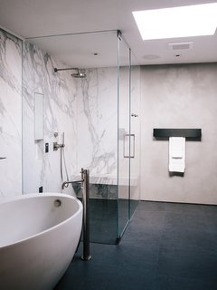 In the master bathroom, a freestanding Waterworks tub is paired with a Fantini fixture. Calacatta marble surrounds the shower; the flooring is Evolution ceramic tile from Apavisa. 