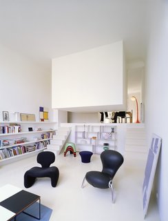 The bedroom in this conversion of a former artist's studio is literally concealed in a white box suspended from the ceiling and located just off the living room. Designed by Emmanuel Combarel Dominique Marrec Architects, the bedroom is "like a hut in the middle of the flat."