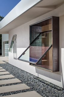 A custom rain-gutter system collects even slight amounts of precipitation in an underground cistern and distributes it to the yard. The Cor-Ten pivoting window is by Brian Linn of Vincent Designs.