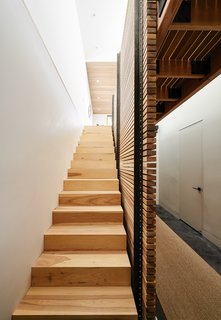 By eliminating the attic and carving out a former crawl space, Red Dot Studio created room for the residents’ bedrooms underneath the primary living areas. The slatted-hickory-and-glass bridge allows light from a row of skylights to penetrate deep into the lower level. 