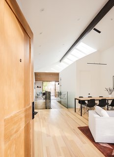 Above an enclosed volume containing a powder room and guest room, a quartet of skylights brightens the living and dining area. A Sonneman Stiletto pendant offers extra light.