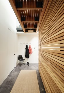 The lower level is distinguished by stained concrete flooring. In the hallway, <br>a Molded Plastic Chair by Charles and Ray Eames for Herman Miller offers a place for the residents to remove their coats and shoes. The seat has an Eiffel base. 