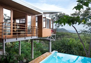 10 Modernist Beach Home Rentals to Escape to This Summer - Photo 4 of 10 - The Floating House stands above the jungle canopy of Costa Rica and was designed by architect Benjamin Garcia Saxe. It's a short walk to the beach and offers elegance that's rooted in nature and simplicity. The structure is made up of three pods that are connected by elevated, outdoor bridges and walkways. Teak flooring and furniture add natural warmth to the main living areas, which are connected to two upstairs bedrooms and an open-air spa bathroom via a 78-foot walkway. The home also features a lounge framed by Concertina floor-to-ceiling glass doors with expansive views of the ocean and jungle. 