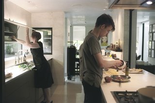 Sarah and her sons prepare a meal in the kitchen, which the Wessels recently upgraded with Bulthaup cabinets, counters, and sink. The stovetop is from Gaggenau and the faucet is from Dornbracht. On the far wall is one of Yoshitomo Nara’s signature eye-patch portraits. 