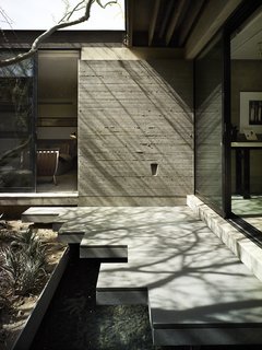 Board-formed concrete walls create the core of the house and establish its organic feel. "There’s really no other cast-in-place concrete on the street," says Sarah, "but you don’t even see it until you’ve made it through the front courtyard." There, beneath a deep overhang, the couple designed a jagged pathway cantilevered over a water inside and reflections of light into the sitting area. 