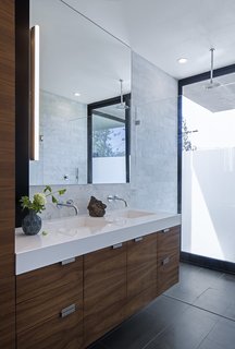 Silestone counters, walnut cabinetry, and Refin floor tiles accent the master bathroom. The Axor Uno faucets are from Hansgrohe, the Alinea vanity light is from Aamsco, and the shower head is by Jaclo.