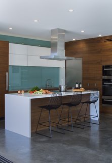 In the kitchen, a blue glass backsplash evokes the designers’ native Iceland. The <br>Bend Goods stools are from YLiving. 