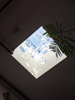 Circular mirrors adhere to the inner walls of a skylight above the dining area, bouncing light and bringing the room yet more illumination. 