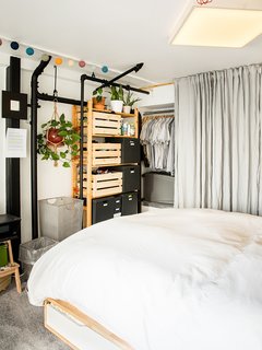 The custom overhead light is a pine box covered in linen, which diffuses the LEDs inside. A gray linen curtain conceals his tools.