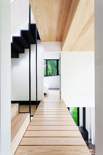 Growing Upward and Outward, a Cabin Expansion Mirrors the Trees - Photo 5 of 10 - Architects Marie-Claude Hamelin and Loukas Yiacouvakis connected the home’s three levels in dramatic fashion. Ash treads float on a steel stringer from the ground floor to the mezzanine.