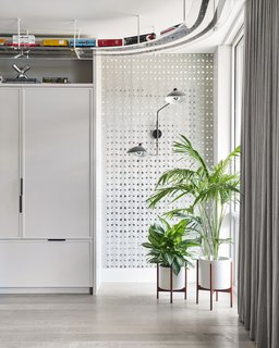 An electric train set from Chicagoland Hobby travels an elevated track designed by Studio Gild. The 35-foot loop passes through the indoor tree house and around the theater room. A Serge Mouille Two-Arm sconce is surrounded by graphic Mylar wallpaper.