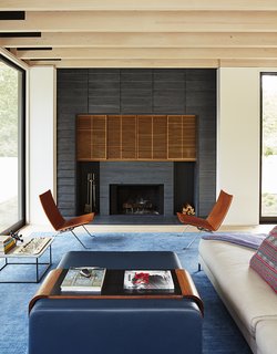 Masi used the same gray slate for the exterior and the fire surround, which boasts a custom wood inset by K. Romeo Inc. The living room also features a custom area rug by SandH Rugs, a Charles sofa by B&B Italia, a pair of PK22 leather chairs by Poul Kjærholm from Fritz Hansen, and an Obi coffee table and tray by Lumifer. 