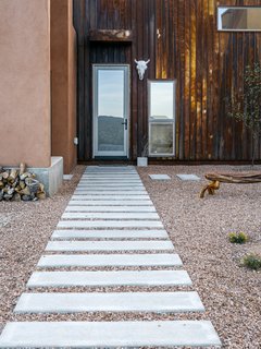 A Rookie Designer and Her Builder Father Create an Artist's Sculptural Loft in the Desert - Photo 2 of 10 - Rusted metal, used on three of the home’s five roofs, extends to the entrance facade, which, in a nod to northern New Mexico’s haciendas, opens to a courtyard. Rather than buy pre-rusted siding, Molly and her father oxidized the steel themselves. 