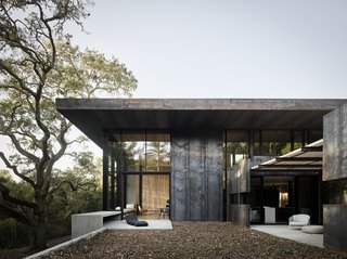 Nature Drove the Design of This Sculptural, Cor-Ten Steel House in Northern California - Photo 1 of 13 - Located in Orinda, California, a three-bedroom house by architect Greg Faulkner took its first aesthetic cue from a large oak tree on the site. Cor-Ten steel panels clad the exterior, while white oak offers a material counterpoint on the interior. A 12-foot-wide sliding pocket wall opens the living/dining area to a terrace with a Wave Chaise longue by Paola Lenti. The landscape design is by Thuilot Associates. 