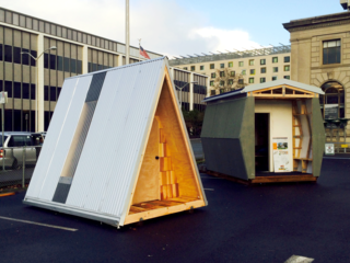 PODs designed by Holst Architecture and SRG Partnership, with Bud Clark Commons visible in the background (center). Bud Clark Commons was designed by Holst Architecture and offers apartment homes to those who have experienced homelessness.