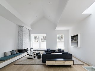 A Historic Victorian in San Francisco Is Meticulously Transformed Into a Modern Family Home - Photo 9 of 26 - Fronting Alamo Square Park, the living room’s pitched ceiling creates an expansive space for socializing and relaxing. The space is accented by a custom sofa and window seat by Franciscan Interiors, rocking chairs from B&B Italia, and a Lake low credenza by BDDW. The fireplace-adjacent bench seating is upholstered in William Yeoward Alverdia fabric in Ocean, complementing the teal accents in the adjoining dining room and kitchen.