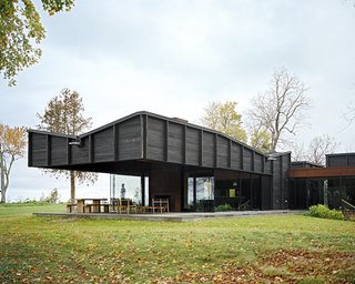 Plagued Ash Trees Were Repurposed to Create This Charred-Cedar Clad Home on Lake Michigan - Photo 1 of 9 - Desai Chia Architecture harvested plagued ash trees from the client’s property and used them for interior millwork, flooring, and trim. Working in collaboration with local architect of record Ray Kendra of Environment Architects and Delta Millworks of Texas, the firm clad the dwelling’s exterior in cedar that was intentionally burned to protect it from fire, insects, and age. The <br>process is called shou sugi ban.