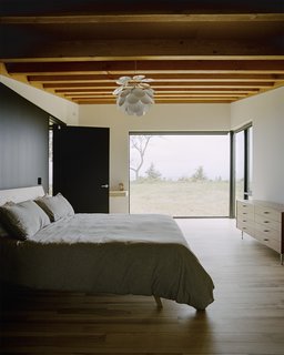 Plagued Ash Trees Were Repurposed to Create This Charred-Cedar Clad Home on Lake Michigan - Photo 3 of 9 - In the master bedroom, the ash bed was designed by Desai Chia and fabricated by Gary Cheadle of Woodbine; the dresser is by George Nelson for Herman Miller. Panes by Western Windows appear throughout the home. 