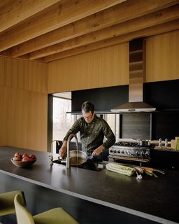 Plagued Ash Trees Were Repurposed to Create This Charred-Cedar Clad Home on Lake Michigan - Photo 7 of 9 - The space is open to the kitchen, where Basaltina countertops are paired with Thermador appliances.