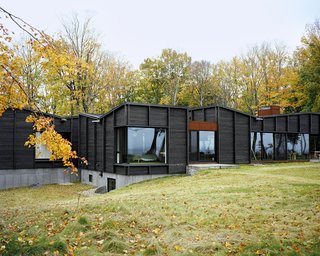 Plagued Ash Trees Were Repurposed to Create This Charred-Cedar Clad Home on Lake Michigan - Photo 2 of 9 - Three interconnected structures—one for communal spaces, one for the master suite, and one for the three children’s bedrooms—are linked via a glass-enclosed breezeway that also serves as the entrance and dining area.
