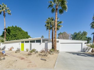 This vacation home in the Racquet Club North neighborhood has an eye-catching, citrus-hued front door and a living area that takes advantage of the California sunshine with a wall of glass. 