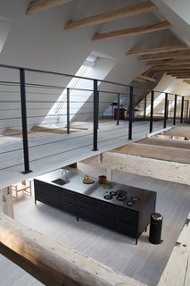 The mezzanine also holds a library stocked with design titles. Below, a Vipp kitchen offers a refined cooking experience.