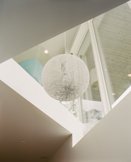 A Tahsis pendant by EQ3 hangs in a triangular shaft above the basement, which is built-out to provide extra space for the single-story house.