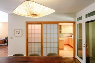 The dining room features a custom pendant by Aqua Creations above an Oregon black walnut table. Shoji doors made by Eric Franklin lead to the kitchen and hide a wet bar. 
