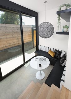 In the breakfast nook, an Ikea table is surrounded by a bench made specifically for the corner by CJS Custom Woodworking & Design. A Moooi pendant light and custom concrete floors distinguish the area. 