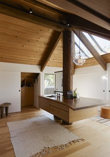  For the heart of the space, Hale designed a double vanity—fabricated with wood from the original house—around an existing column. The pendant is by Lindsey Adelman.