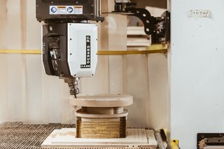 Watch: It Takes 9 Hours For Woodworkers to Make This Shaker-Inspired Chair - Photo 11 of 19 - Shape the Seat: In a nine-minute automated process, a CNC machine routs and shapes the panel into an ergonomically correct seat. It also drills holes for the spindles and legs. By hand, this step alone would take hours. 