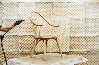 Watch: It Takes 9 Hours For Woodworkers to Make This Shaker-Inspired Chair - Photo 3 of 19 - It takes nine hours to complete a single Continuous Arm Chair, requiring at least three people from start to finish. At a spray booth in the 90,000-square-foot factory, an artisan applies oil to a chair.