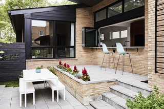 Midcentury Mashup: A 1950s Ranch House in Chicago Gets a Palm Springs-Style Butterfly Roof - Photo 5 of 15 - In the front courtyard, a raised bluestone patio was built off the new kitchen for casual meals and entertaining. The Eames Molded Plastic Chairs are from Herman Miller. The dining table and benches are from Room & Board. 